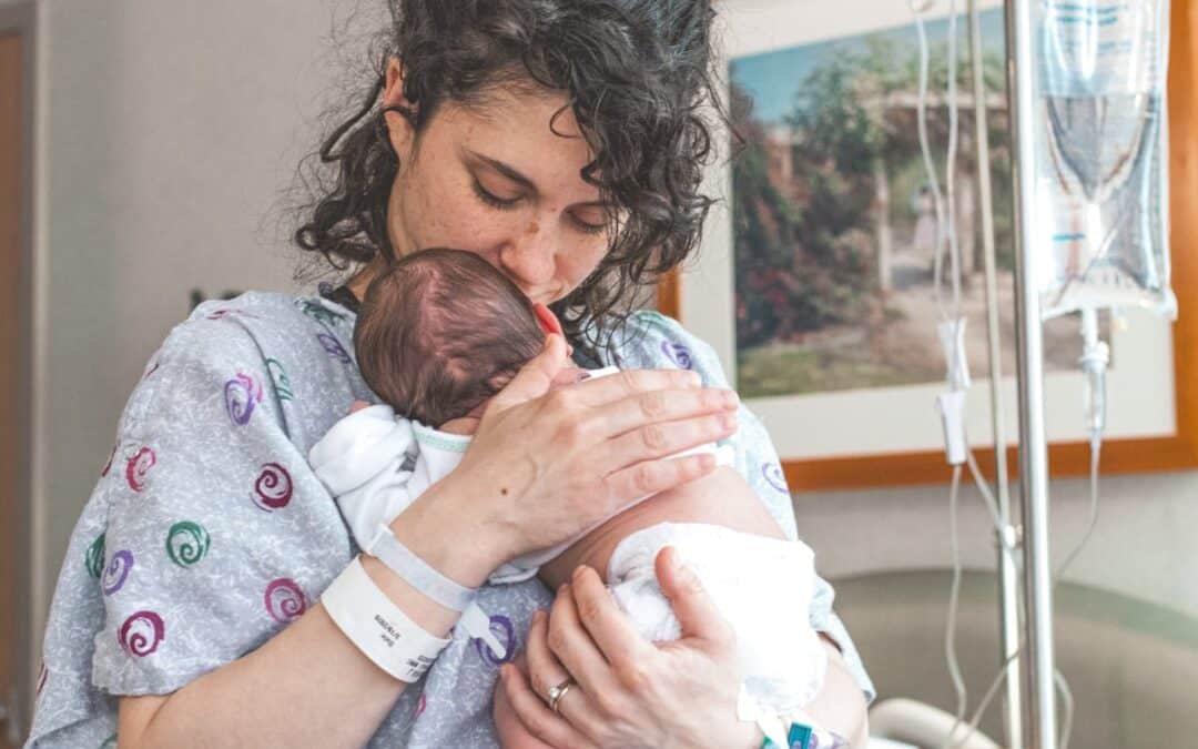 Mama w połogu trzymająca noworodka w szpitalu
